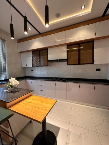 Una cocina con gabinetes blancos y una mesa de madera. en emerald, en Lagos
