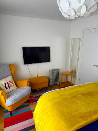 a bedroom with a yellow bed and a tv at Bloom19 Traditional Belfast Entire House 10 mins from City Centre in Belfast