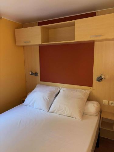 une chambre avec un lit avec des oreillers blancs dans l'établissement Mobil-home 2 personnes climatisé, à Orgnac-lʼAven