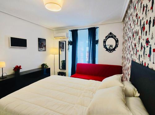 ein Schlafzimmer mit einem großen Bett und einer roten Couch in der Unterkunft En PLENO CENTRO - Especial para GRUPOS o FAMILIAS - GRAN VÍA - CALLAO - SOL - PLAZA ESPAÑA in Madrid