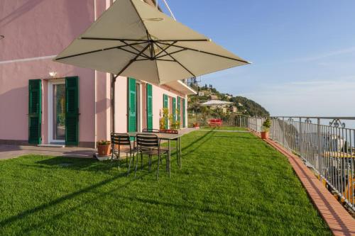 a patio with a table and chairs and an umbrella at Stella di mare - appartamenti vista incantevole su Moneglia in Moneglia
