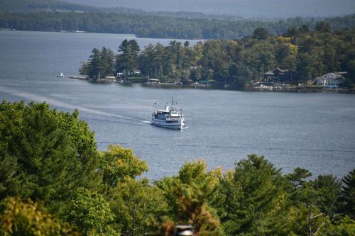 a boat traveling down a large lake with trees at Grand View Resort in Weirs Beach