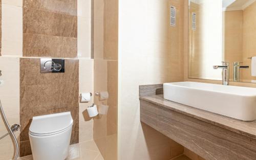 a bathroom with a white toilet and a sink at Pyramisa Hotel Apartments in Dubai