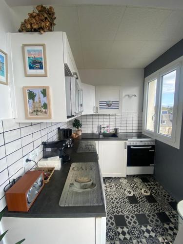 une cuisine avec des armoires blanches et un comptoir noir dans l'établissement Entre terre & Mer, à Saint-Brieuc