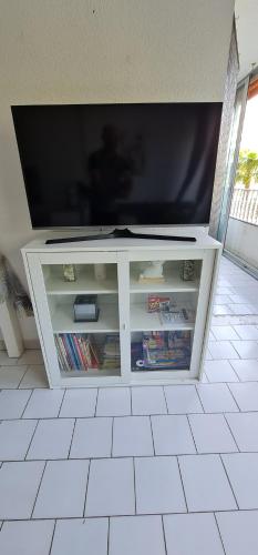 un téléviseur à écran plat sur un centre de divertissement blanc dans l'établissement Appt LGM, au couchant, piscine, 300m plage, à La Grande Motte