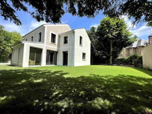 une maison blanche sur une pelouse verte dans l'établissement GARCHES, proche PARIS, Villa 10 personnes, quartier calme et cosy, à Garches