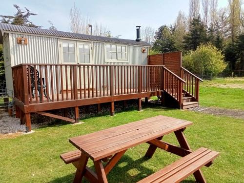 a wooden picnic table in front of a house at Woodpecker Shepherds Hut in Boston