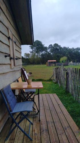 une table et une chaise assises sur une terrasse couverte avec une table dans l'établissement Gîte - La Ferme à la Plage, à Le Porge