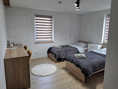 a bedroom with two beds and a desk and two windows at Stary Młyn in Glinik