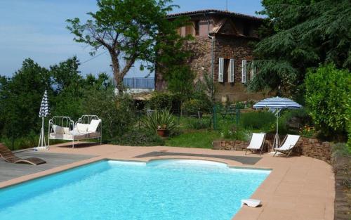 - une piscine avec des chaises et un parasol à côté d'une maison dans l'établissement La maison de nathalie gite romeo g2483, à Les Mayons