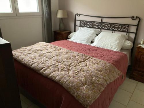 - un lit avec une couverture rouge et des oreillers blancs dans l'établissement Maison Le Prunier avec piscine - Domaine E Case Di Cuttoli, à Cuttoli-Corticchiato