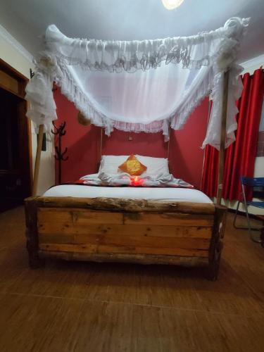 a bed with a canopy in a room with red walls at Edaala Comfort - B&B in Nairobi