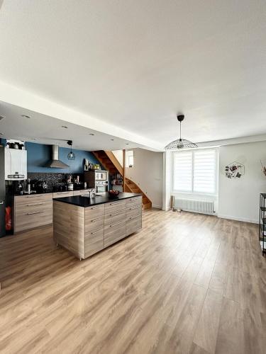 une cuisine vide et un salon avec parquet dans l'établissement Beau duplex et studio proche de la mer, à Donville-les-Bains