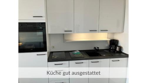 a kitchen with white cabinets and a sink and a stove at Deck 29 in Timmendorfer Strand