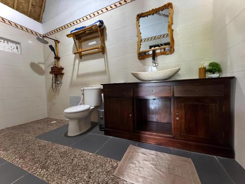 a bathroom with a sink and a toilet and a mirror at Meket Bungalows in Nusa Penida