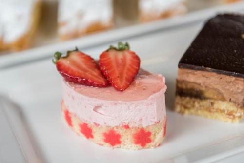 a piece of cake with strawberries on top on a plate at Hotel Schönblick in Maranza