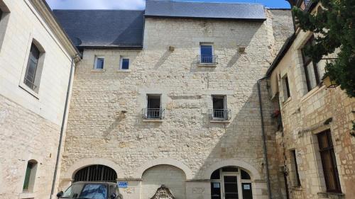 a large stone building with windows and a car parked in front at La Clef des Remparts in Chinon