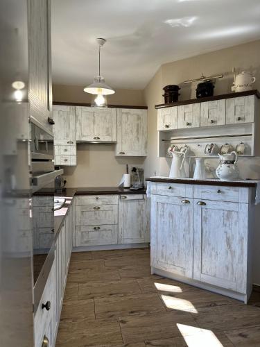 a kitchen with white cabinets and white appliances at Ostoja Jeziorak Jezierzyce in Makowo
