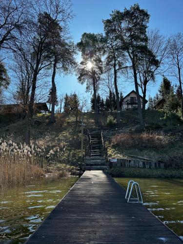 a wooden bridge over a body of water at Ostoja Jeziorak Jezierzyce in Makowo