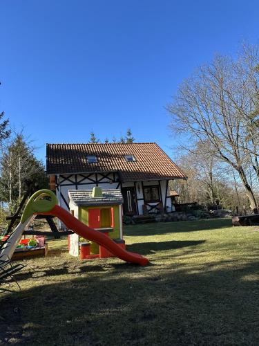 a playground with a slide in front of a house at Ostoja Jeziorak Jezierzyce in Makowo