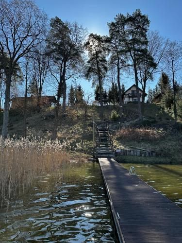a wooden bridge over a body of water at Ostoja Jeziorak Jezierzyce in Makowo