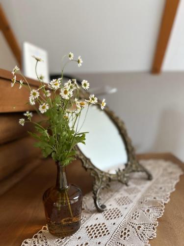 a vase of flowers on a table with a mirror at Ostoja Jeziorak Jezierzyce in Makowo