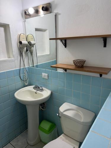 a blue tiled bathroom with a sink and a toilet at La Posadita de Bolonia in Managua