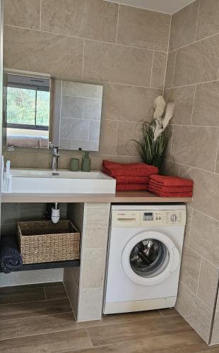 une salle de bain avec une machine à laver et un lavabo dans l'établissement Appartement bas de villa avec accès piscine, à Ventiseri