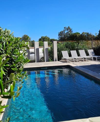 une piscine avec des chaises longues et une piscine dans l'établissement Appartement bas de villa avec accès piscine, à Ventiseri