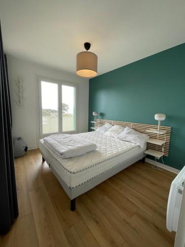 une chambre avec un grand lit avec un mur bleu dans l'établissement Charmant appartement face à la mer, à Saint-Palais-sur-Mer