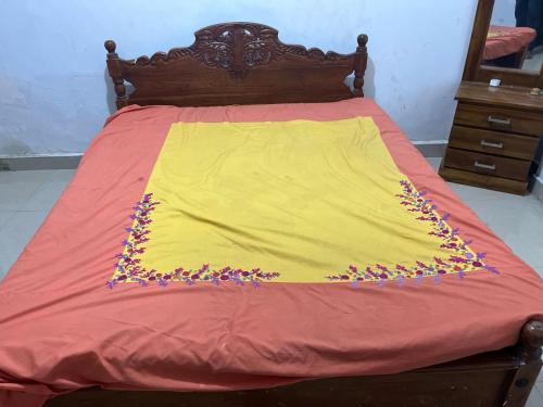 a bed with a yellow blanket with purple flowers on it at Imaz villa in Puttalam
