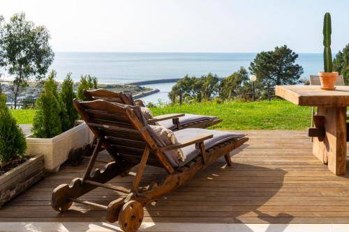 a rocking chair on a deck with the ocean in the background at Nativo Sea Garden in Nazaré