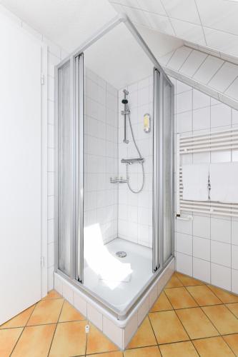 a bathroom with a shower with white tiles at Pension Burggaststätte Heyken in Neuharlingersiel