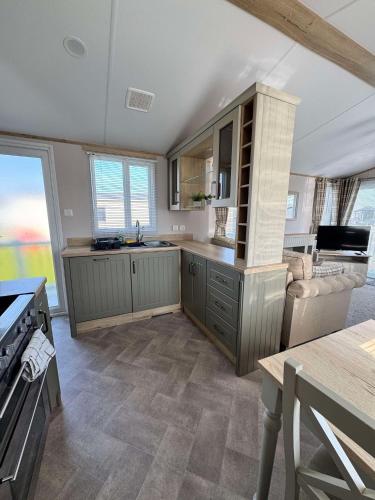 a large kitchen with a stove and a couch at 6 birth caravan chapel st Leonards trunch lane in Chapel Saint Leonards