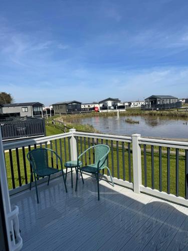 two chairs sitting on a deck next to a body of water at 6 birth caravan chapel st Leonards trunch lane in Chapel Saint Leonards