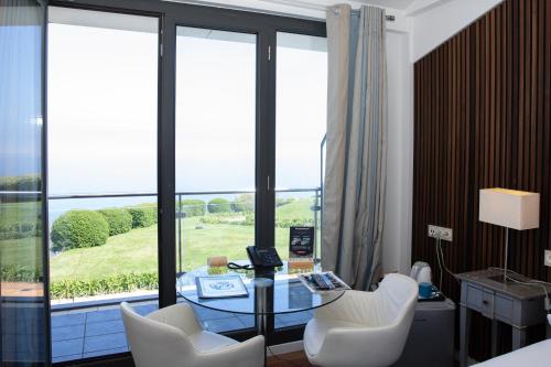 a living room with a glass table and white chairs at Hotel Arbe in Mutriku