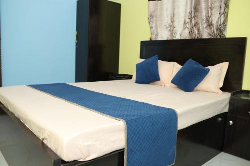 a bed with blue and white pillows on it at Park kasba Inn in Kolkata
