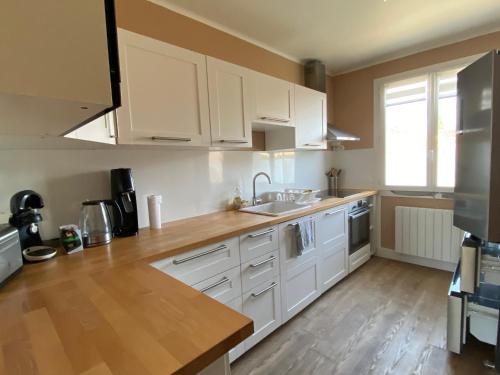 une cuisine avec des armoires blanches et un plancher en bois dans l'établissement Grand appartement spacieux, à Sénas