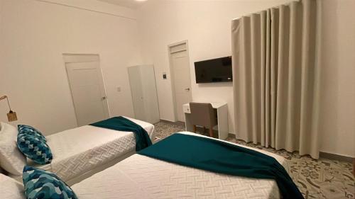 a hotel room with two beds and a flat screen tv at Hotel Boutique Brisas Colonial in Santo Domingo