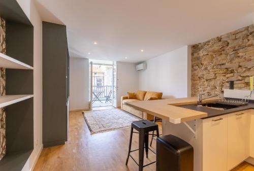 Il comprend une cuisine et un salon avec un mur en pierre. dans l'établissement Duplex Neuf Hyper Centre Idéal Curistes, à Dax