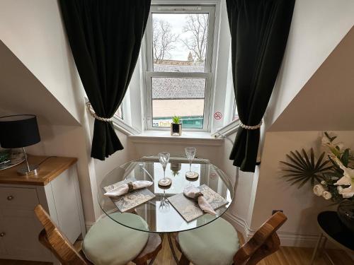 a glass table and chairs in a room with a window at The Canongate Coorie in Jedburgh