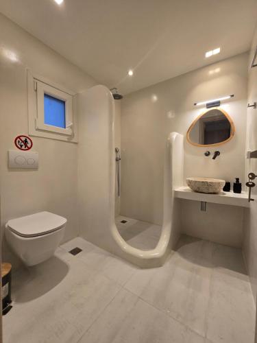 a white bathroom with a toilet and a sink at Magia's Residence in Naousa