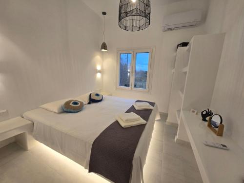 een witte slaapkamer met een groot bed en een raam bij Magia's Residence in Naousa