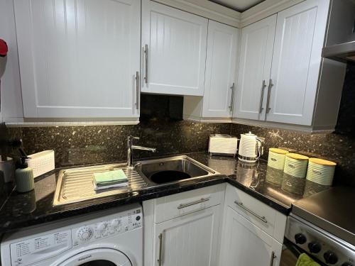 a kitchen with white cabinets and a sink at The Canongate Coorie in Jedburgh