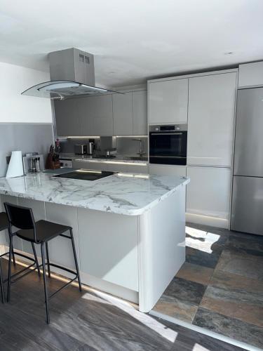 a white kitchen with a large white counter top at Modern four bedroom semi-detached house with off street parking 8 min drive to Wembley stadium, 5 miles to Central London in London