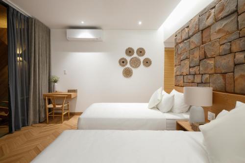 a hotel room with two beds and a stone wall at Sendoro Retreat in Láng Lớn