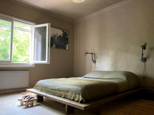 une chambre avec un lit et une fenêtre dans l'établissement Quelquepart au vert 2, à Saint-Christol-de-Rodières
