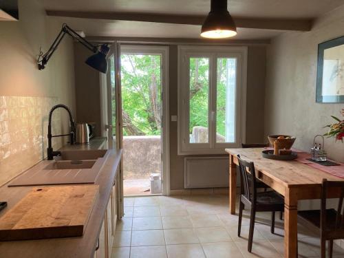 une cuisine avec une table en bois et une grande fenêtre dans l'établissement Quelquepart au vert 2, à Saint-Christol-de-Rodières