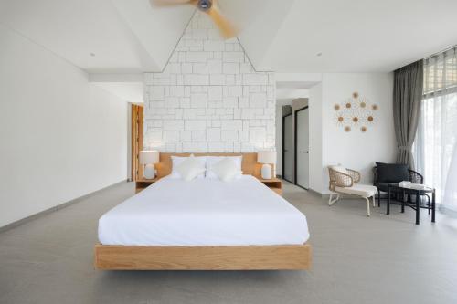 a bedroom with a large white bed and a chair at Sendoro Retreat in Láng Lớn