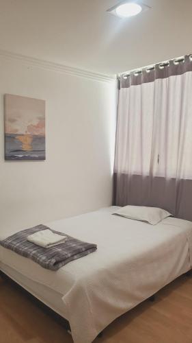 a bed in a room with a window with a white curtain at Bello Horizonte, Dep grande con parqueadero in Cuenca